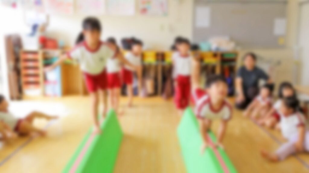 緑色の細長いマットの上を、体操服の子どもたちが順番に進む練習の様子